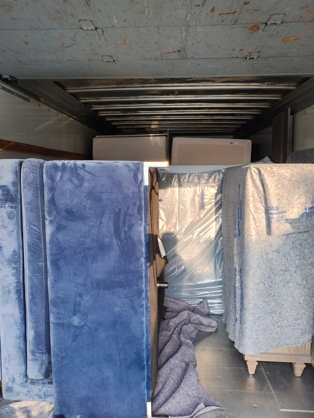 Follow Our Work On Instagram Happy couple holding packed moving boxes inside their living room during a Murfreesboro home relocation.